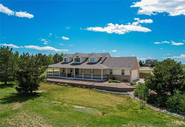 895 Antelope Dr W, Bennett, CO 80102 - back of house featuring a porch, a yard, brick siding, an attached garage, and a shingled roof
