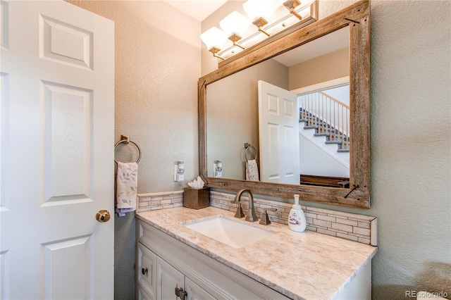 895 Antelope Dr W, Bennett, CO 80102 - bathroom with a textured wall, vanity, and decorative backsplash