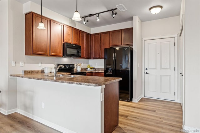 kitchen featuring visible vents, a peninsula, black appliances, and light wood finished floors