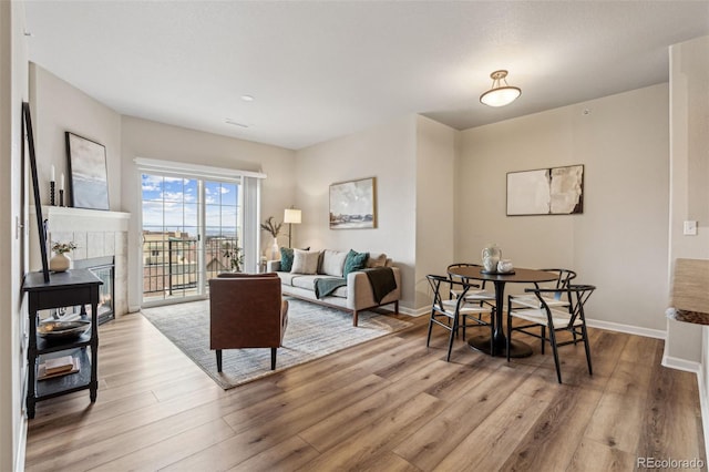 living room featuring baseboards, a tiled fireplace, and wood finished floors