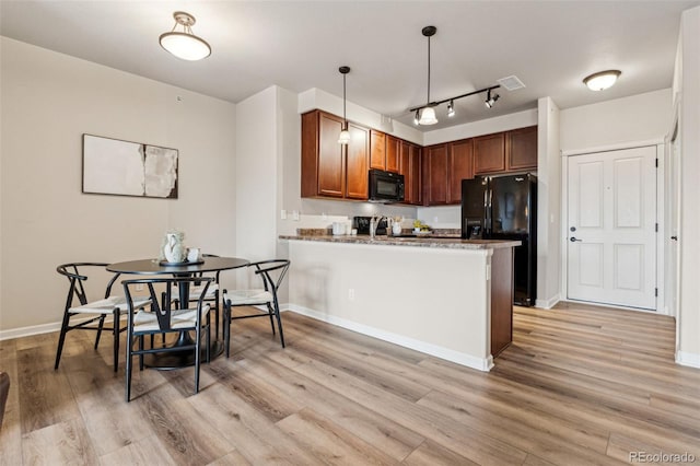 kitchen featuring black appliances, light wood finished floors, a peninsula, and visible vents