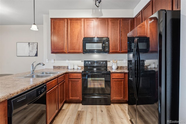 kitchen with light wood-type flooring, black appliances, light countertops, and a sink