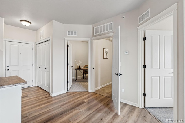 corridor with light wood-style flooring and visible vents