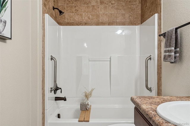 full bathroom featuring a textured wall,  shower combination, and vanity