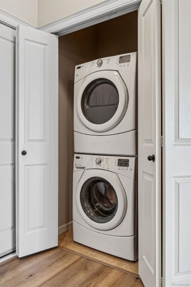 washroom with laundry area, stacked washer / dryer, and light wood-style flooring