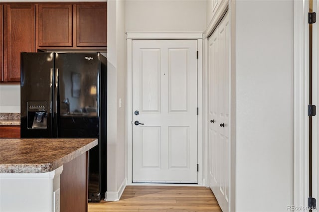 kitchen featuring light wood-style floors and black fridge with ice dispenser