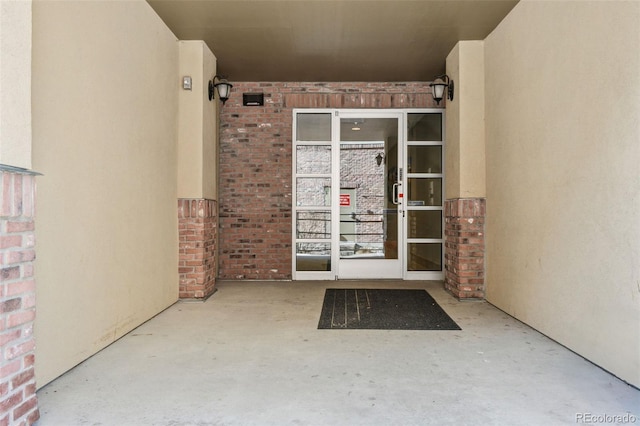 entrance to property featuring brick siding and stucco siding