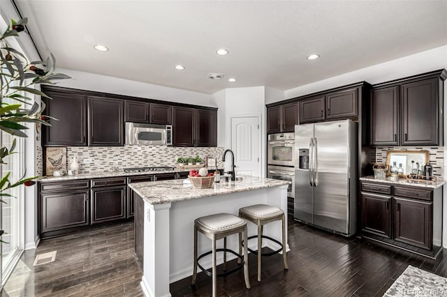 kitchen featuring stainless steel appliances, dark wood finished floors, backsplash, dark brown cabinetry, and a sink