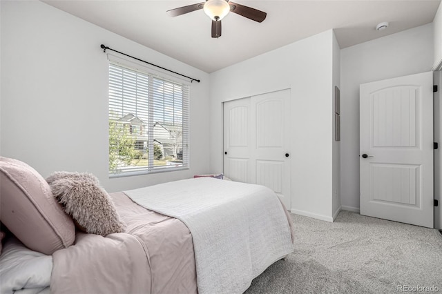 bedroom with light carpet, a closet, baseboards, and a ceiling fan