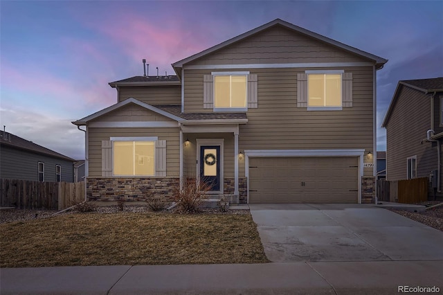 view of front of home featuring stone siding, driveway, an attached garage, and fence