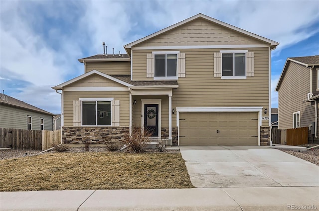 view of front of property featuring stone siding, driveway, an attached garage, and fence