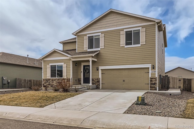 view of front of property with stone siding, concrete driveway, and fence