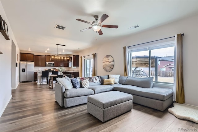 living room featuring dark wood finished floors, visible vents, and a ceiling fan