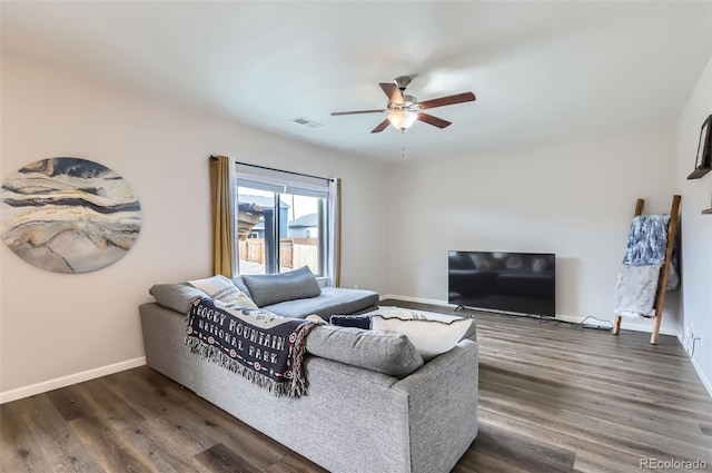 living room featuring ceiling fan, visible vents, baseboards, and dark wood finished floors