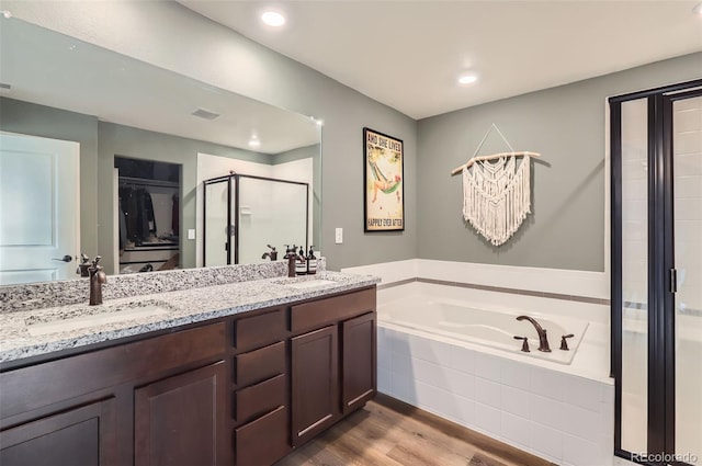 full bath featuring a garden tub, a stall shower, a sink, wood finished floors, and double vanity