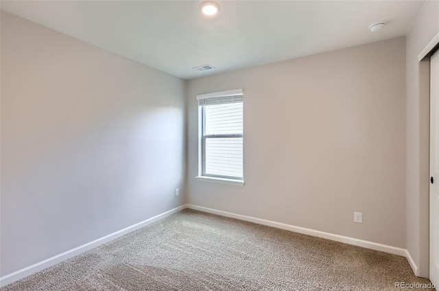 spare room with light carpet, visible vents, and baseboards