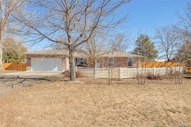 ranch-style house featuring a fenced front yard, brick siding, driveway, and a garage