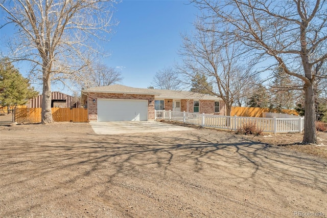 ranch-style house with a fenced front yard, concrete driveway, brick siding, and an attached garage