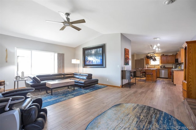 living room with lofted ceiling, light wood finished floors, baseboards, and a ceiling fan