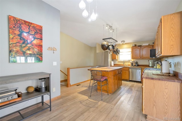 kitchen featuring wooden counters, stainless steel dishwasher, a kitchen island, and light wood-style floors