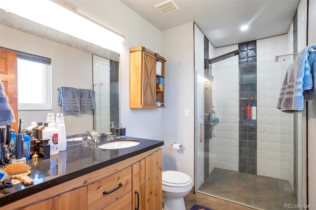 bathroom with a stall shower, visible vents, vanity, and toilet