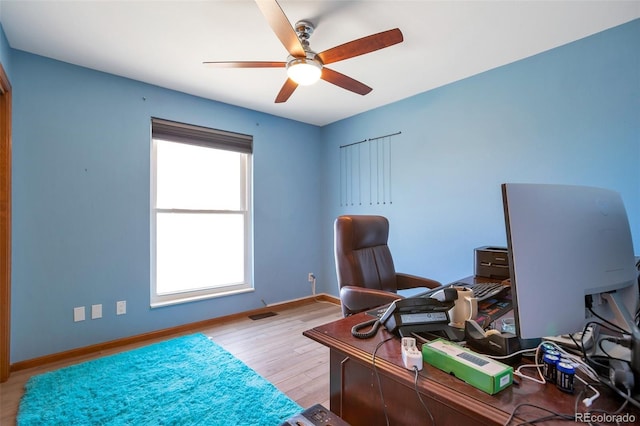 office area featuring light wood finished floors, visible vents, baseboards, and a ceiling fan