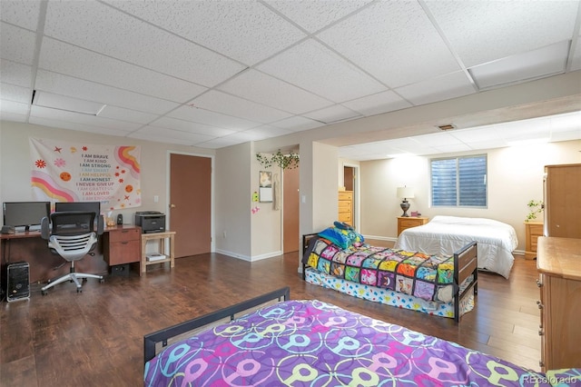 bedroom featuring a paneled ceiling, baseboards, and wood finished floors