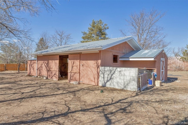 view of outbuilding with fence and an outbuilding