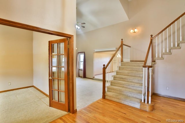 staircase featuring a high ceiling, hardwood / wood-style floors, and ceiling fan