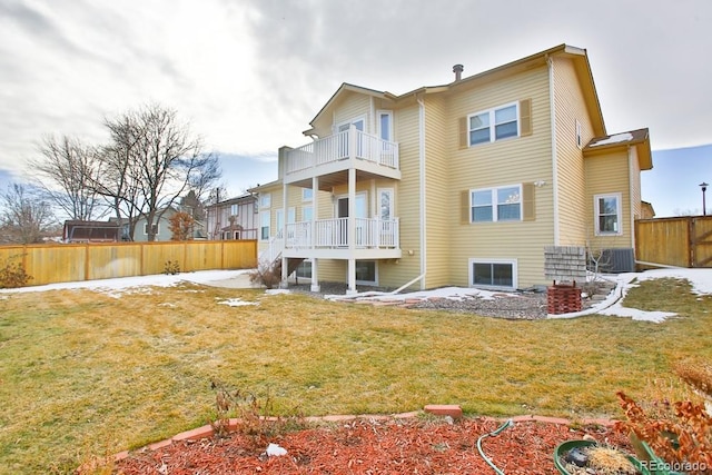 rear view of house featuring a balcony, a yard, and central air condition unit