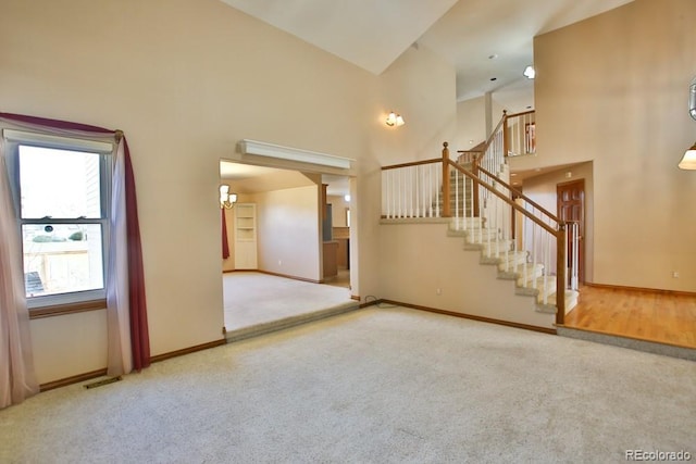 unfurnished living room with a towering ceiling and carpet