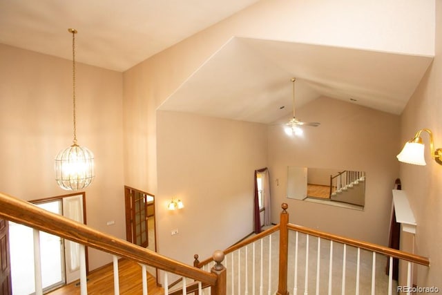 stairway featuring hardwood / wood-style floors, ceiling fan with notable chandelier, and vaulted ceiling