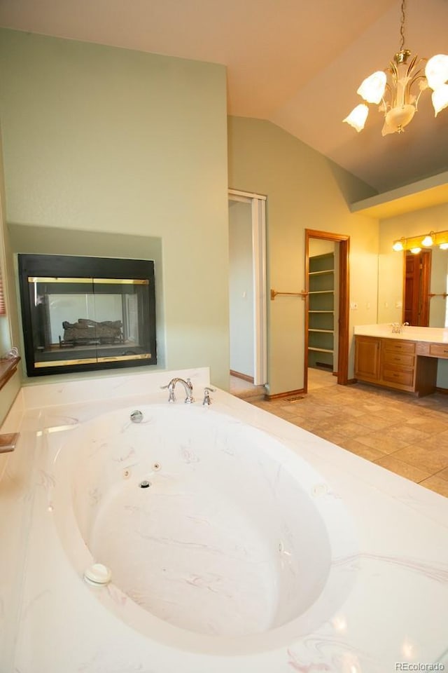 bathroom featuring vaulted ceiling, a multi sided fireplace, a tub, vanity, and an inviting chandelier