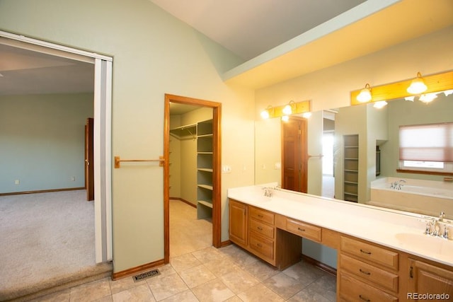 bathroom with a bathing tub, lofted ceiling, and vanity