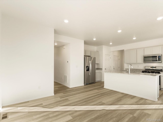 kitchen with appliances with stainless steel finishes, sink, a center island with sink, and light hardwood / wood-style floors