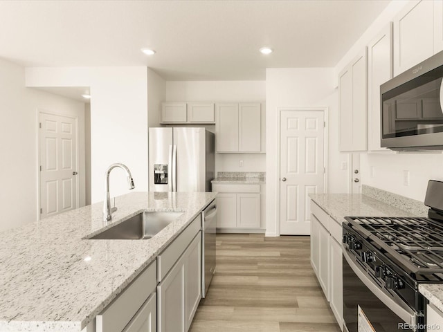 kitchen with light stone countertops, white cabinetry, appliances with stainless steel finishes, and sink