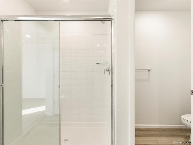 bathroom with hardwood / wood-style flooring, toilet, and walk in shower