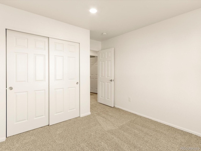 unfurnished bedroom featuring light colored carpet and a closet