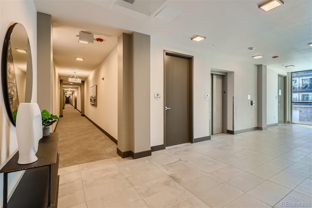 corridor featuring elevator and light tile patterned floors