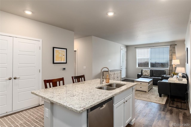 kitchen featuring dishwasher, sink, dark wood-type flooring, white cabinetry, and a kitchen island with sink