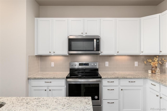 kitchen with light stone counters, backsplash, white cabinets, and stainless steel appliances