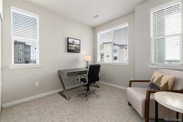 home office with a wealth of natural light and light carpet