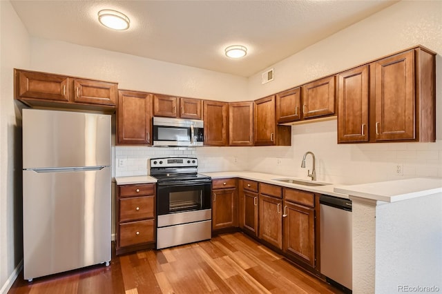 875 E 78th Ave Unit 9-2, Denver, CO 80229 - kitchen with stainless steel appliances, a sink, decorative backsplash, wood finished floors, and light countertops