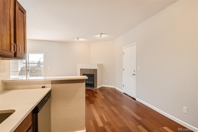 875 E 78th Ave Unit 9-2, Denver, CO 80229 - kitchen featuring stainless steel dishwasher, a tiled fireplace, a peninsula, dark wood-type flooring, and light countertops