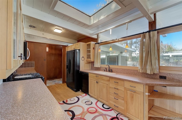 kitchen with beam ceiling, black appliances, a skylight, and light brown cabinets