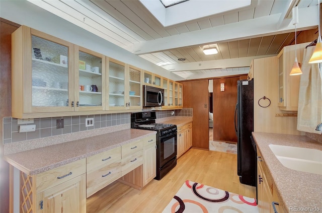 kitchen with pendant lighting, light wood-type flooring, black appliances, beam ceiling, and sink