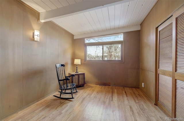 sitting room featuring light hardwood / wood-style flooring, beam ceiling, wood walls, and wood ceiling