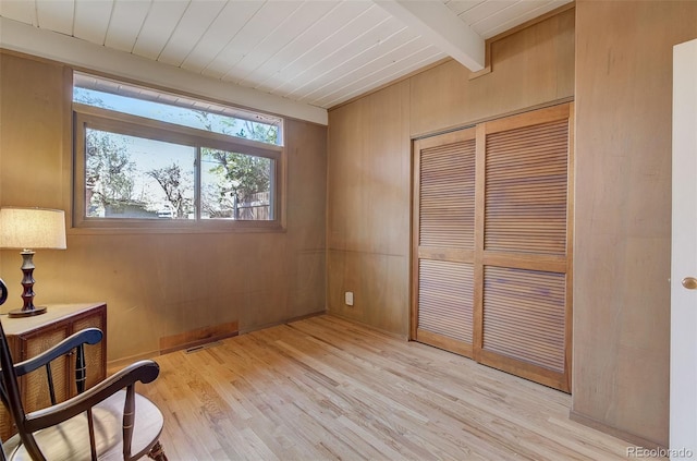 living area with light wood-type flooring, wood walls, beam ceiling, and wooden ceiling