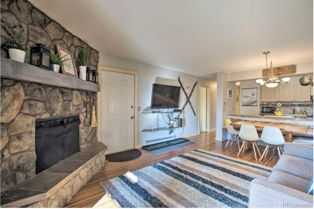 170 Gcr 838 Unit 6, Fraser, CO 80442 - living room with a chandelier, wood finished floors, a textured ceiling, a stone fireplace, and baseboards