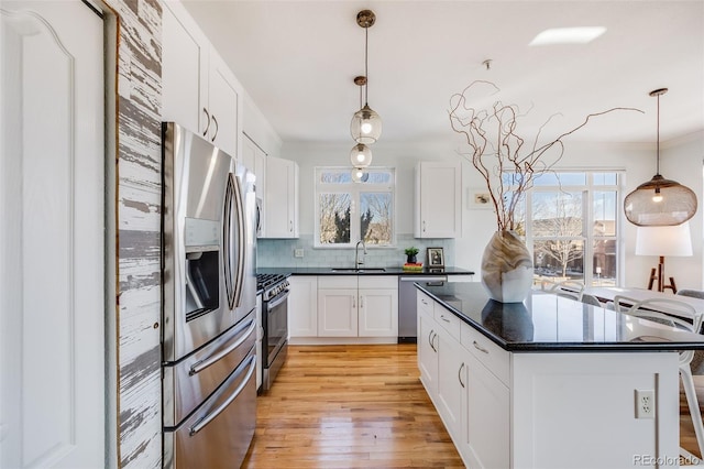 111 S Monroe St Unit B203, Denver, CO 80209 - kitchen featuring stainless steel appliances, backsplash, white cabinetry, light wood finished floors, and ornamental molding